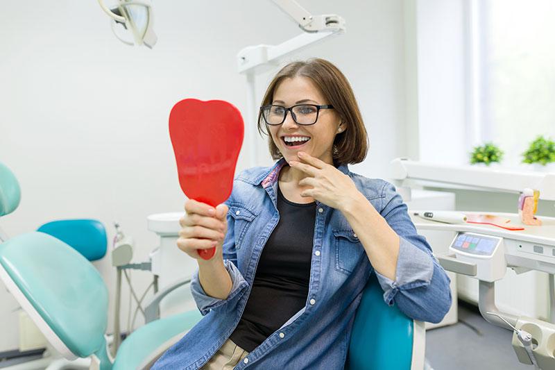 Patient with dental implants looking in the mirror
